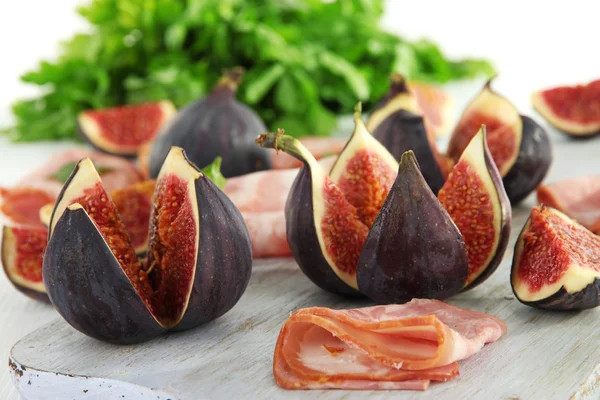 Smakelijke vijgen met ham op witte houten tafel — Stockfoto