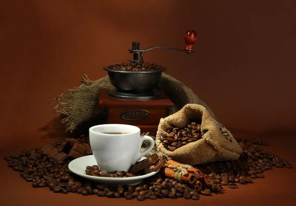 Cup of coffee, grinder, turk and coffee beans on brown background — Stock Photo, Image