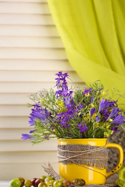 カップとベリー木製テーブルの上で野生の花の美しい花束 — ストック写真