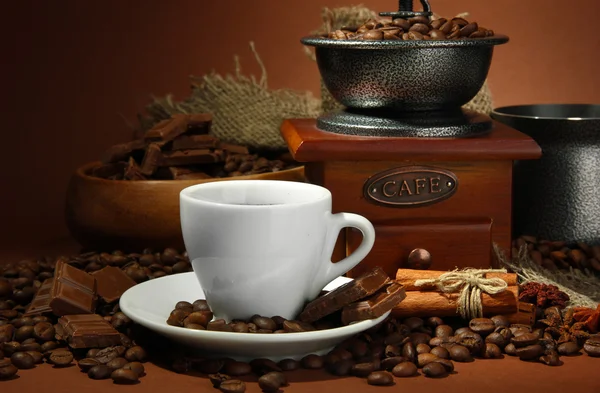 Cup of coffee, grinder, turk and coffee beans on brown background — Stock Photo, Image