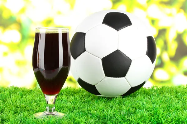 Glass of beer on lawn with ball — Stock Photo, Image