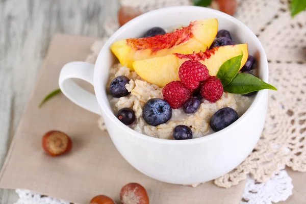 Haferflocken in Tasse mit Beeren auf Servietten auf Holztisch — Stockfoto