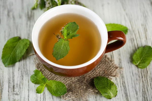 Taza de té de hierbas con flores de menta fresca en la mesa de madera —  Fotos de Stock