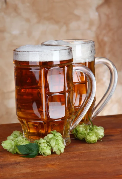 Glasses of beer and hops, on wooden table — Stock Photo, Image