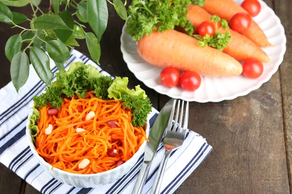 Karottensalat auf Teller auf Serviette auf Holztisch — Stockfoto