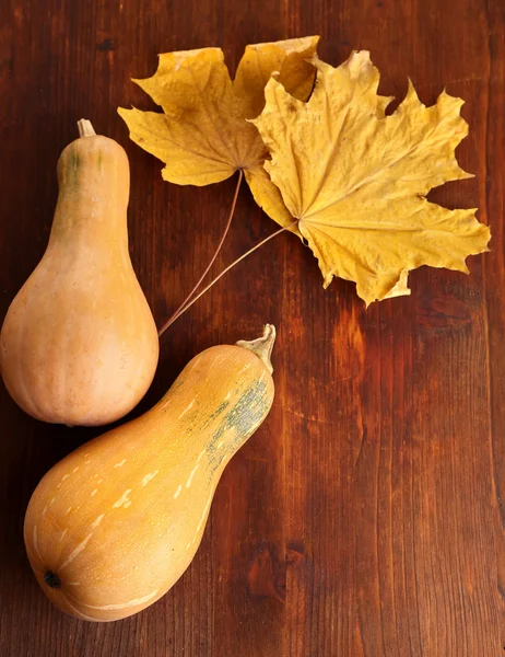 Calabazas maduras con hojas amarillas de otoño sobre mesa de madera de cerca — Foto de Stock