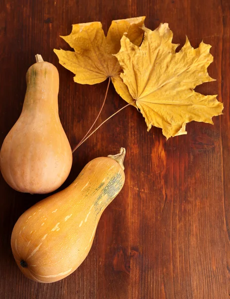 Rijp pompoenen met gele herfst bladeren op houten tafel close-up — Stockfoto