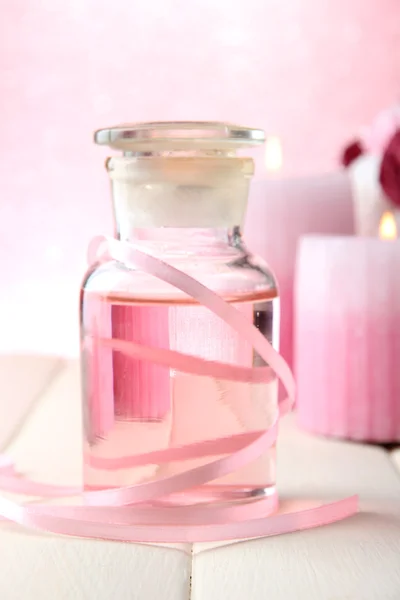 Bouteille en verre avec essence de couleur, sur fond rose — Photo