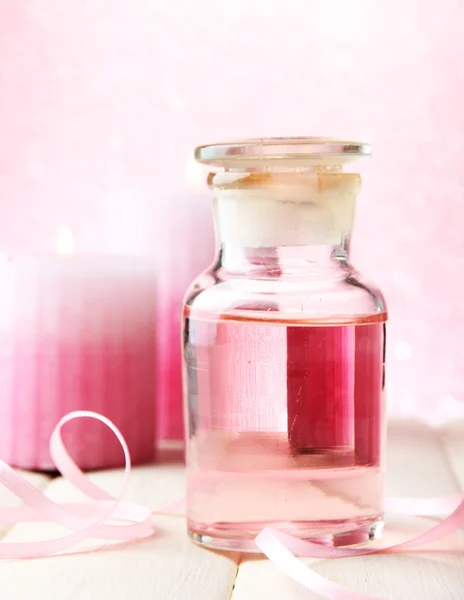 Botella de vidrio con esencia de color, sobre fondo rosa —  Fotos de Stock