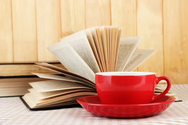 Taza de café y libros sobre mantel sobre fondo de madera —  Fotos de Stock