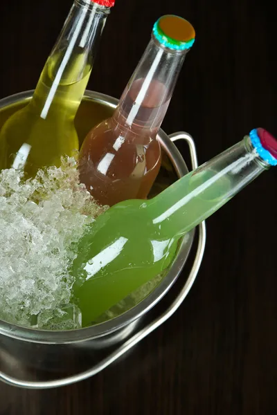 Bebidas embotelladas en cubo de hielo sobre fondo marrón — Foto de Stock