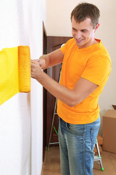Νεαρός άνδρας χρώματα τοίχων στο καινούριο διαμέρισμα — Φωτογραφία Αρχείου