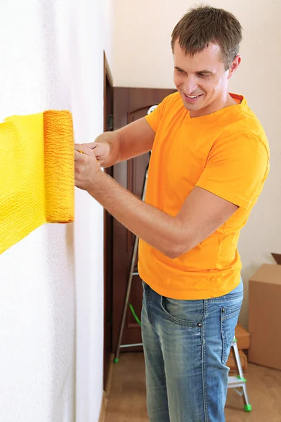 Joven hombre pinta la pared en nuevo piso — Foto de Stock