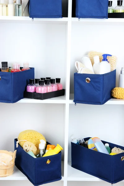Boîtes textiles bleues avec produits cosmétiques pour soins personnels dans des étagères blanches — Photo