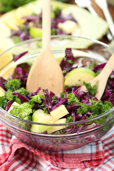 Salade de légumes frais dans un bol et assiette sur serviette sur table en bois close-up — Photo