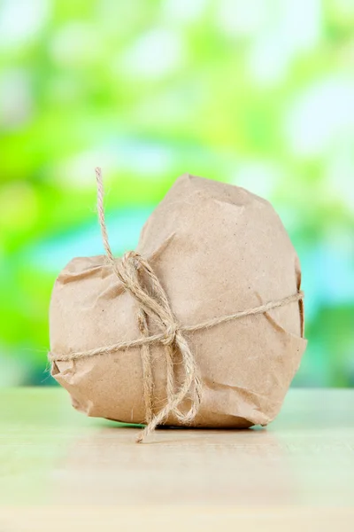 Heart wrapped in brown kraft paper, on nature background — Stock Photo, Image