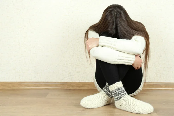 Sad woman sitting on floor near wall — Stock Photo, Image