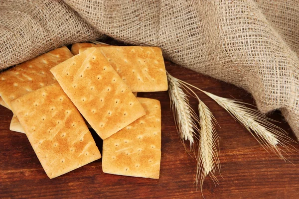 Delicious crackers with spikes on wooden table on sackcloth background — Stock Photo, Image