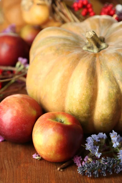 Осенний состав яблок, тыкв, цветов и сухих ветвей на деревянном столе крупным планом — стоковое фото