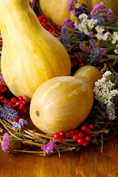 Zucca in ghirlanda di rami secchi con fiori e viburno su tavolo di legno primo piano — Foto Stock