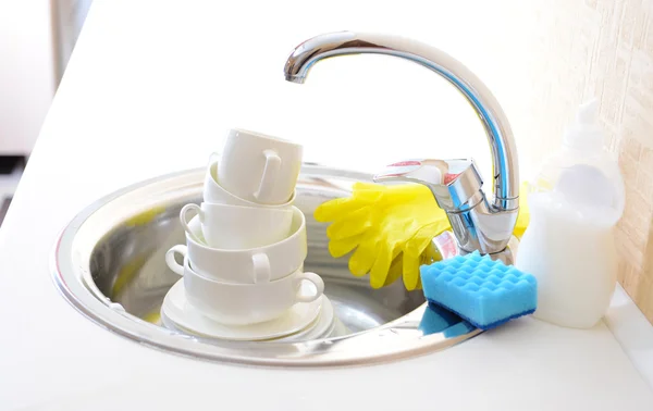 Stack of dishes soaking in kitchen sink — Stock Photo, Image