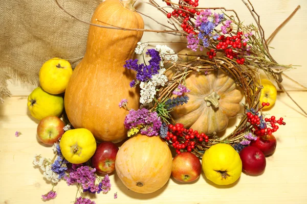 Composizione autunnale di mele, zucche, fiori e rami secchi su tavolo di legno su fondo di legno — Foto Stock