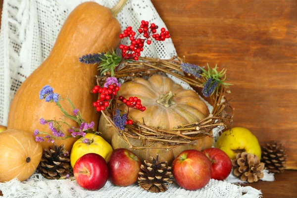Composition automnale de pommes, citrouilles, fleurs et branches sèches sur table en bois sur fond en bois — Photo