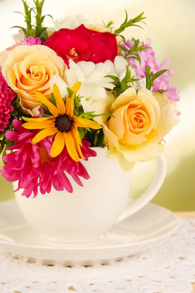 Belo buquê de flores brilhantes na caneca a cores, na mesa de madeira, no fundo brilhante — Fotografia de Stock