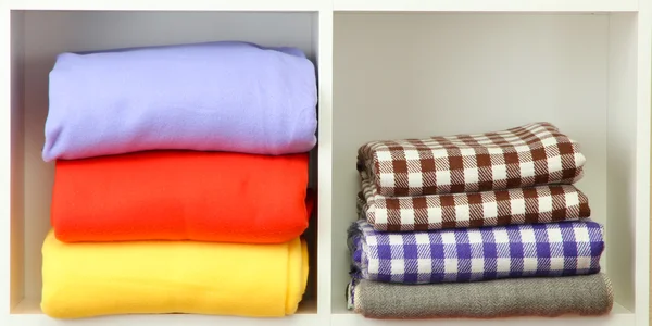 Bright towels and plaids on shelves, isolated on white — Stock Photo, Image