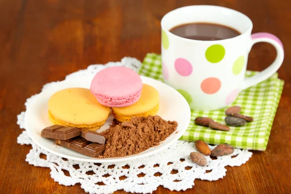 Cacao en taza con dulces y cacao en polvo en plato sobre mesa de madera —  Fotos de Stock