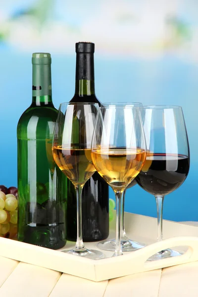 Botellas de vino y copas de vino en bandeja, sobre fondo brillante —  Fotos de Stock