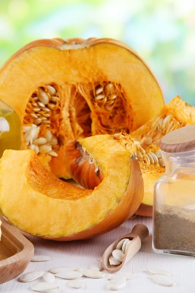 Cut pumpkin with ingredients for cooking on wooden table on natural background — Stock Photo, Image