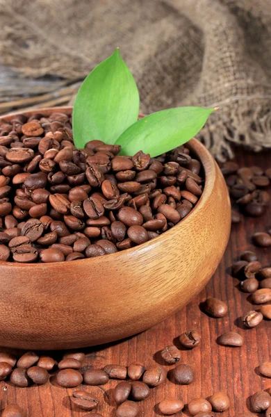 Granos de café en tazón sobre fondo de madera —  Fotos de Stock