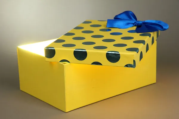 Подарункова коробка з яскравим світлом на ній на сірому фоні — стокове фото