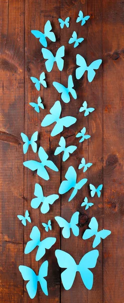 Papel azul mariposas sobre fondo tablero de madera — Foto de Stock