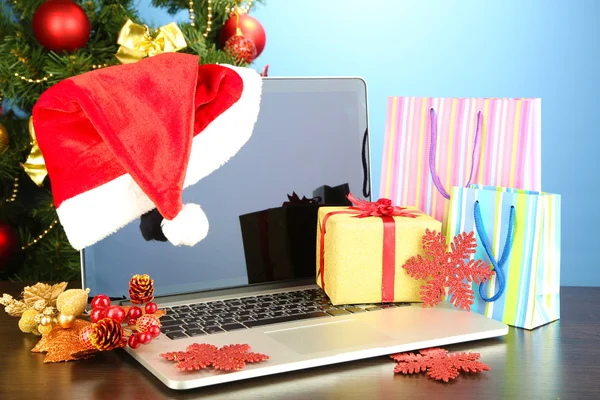 Ноутбук с подарками на столе на синем фоне — стоковое фото