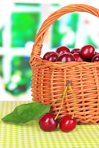 Cherry berries in wicker basket on table in room — Stock Photo, Image