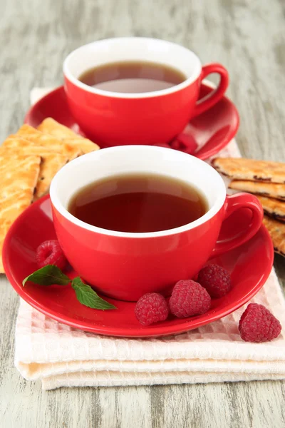 Kopjes thee met koekjes en frambozen op tabel close-up — Stockfoto