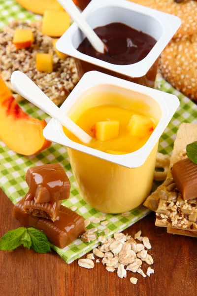 Desserts savoureux à la crème avec des morceaux de fruits frais, biscuits et flocons, sur fond de bois de couleur — Photo