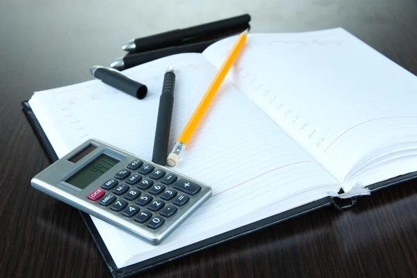 Notebook with pens,pencil and calculator on wooden background — Stock Photo, Image