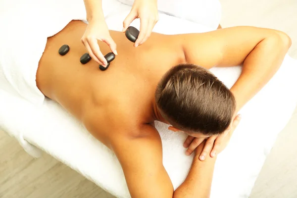 Young man having stone massage in spa salon — Stock Photo, Image