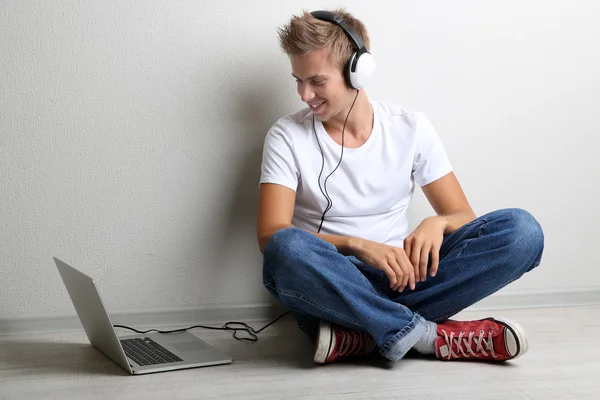 Joven guapo escuchando música sobre fondo gris — Foto de Stock