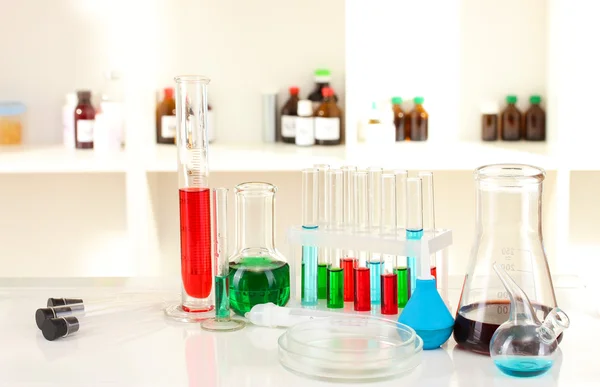 Different laboratory glassware with color liquid on laboratory background — Stock Photo, Image