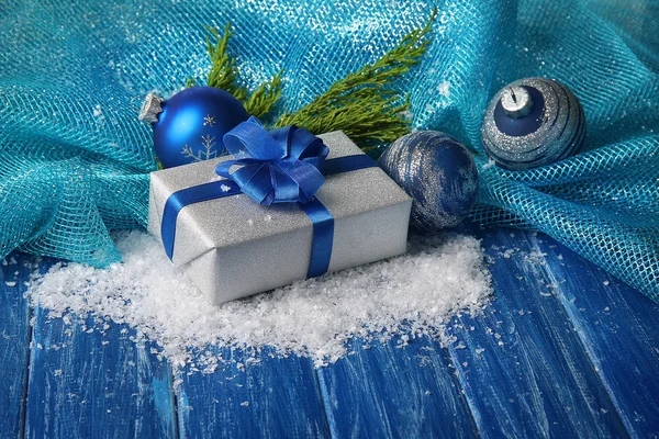 Composition with Christmas balls, gift box and snow on color wooden background — Stock Photo, Image