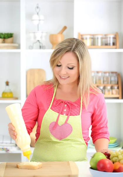 Happy smiling woman in kitchen preparing sandwich — Stock Photo, Image