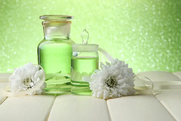 Botellas de vidrio con esencia de color, sobre mesa de madera, sobre fondo verde — Foto de Stock