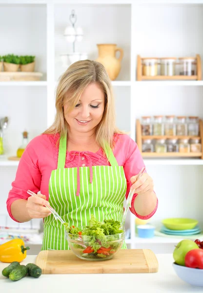 Glücklich lächelnde Frau in der Küche bereitet Gemüsesalat zu — Stockfoto