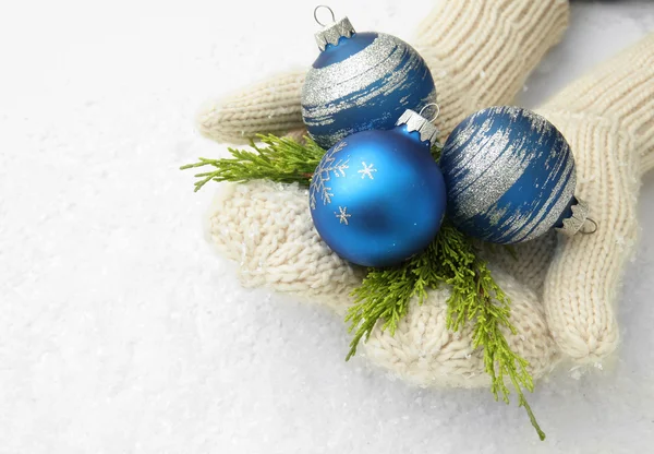 Female hands in mittens Christmas tree balls, on color background — Stock Photo, Image