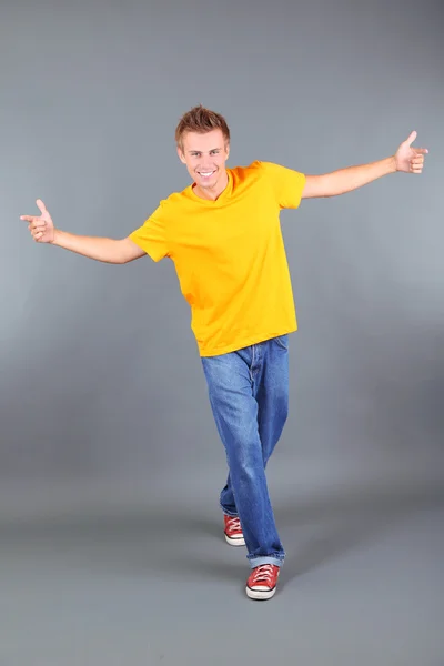 Pohledný mladý muž tančí na šedém pozadí — Stock fotografie