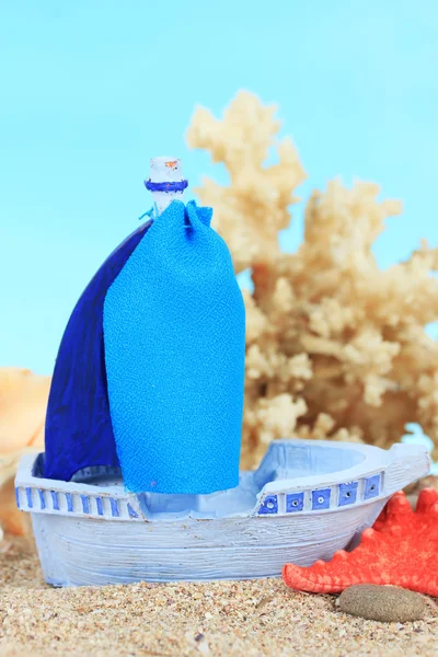 Blue toy ship on sand, on blue background — Stock Photo, Image